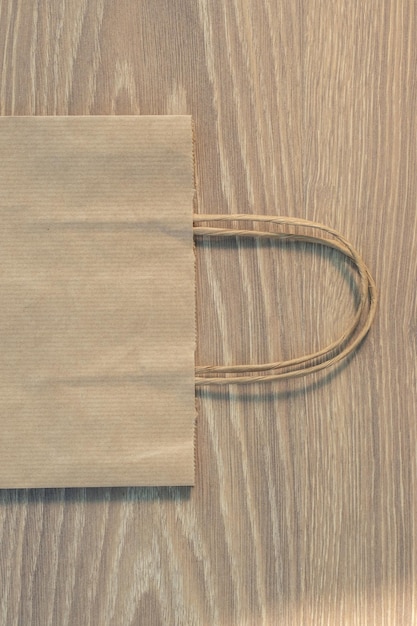 papierowa brązowa torba na zakupy na drewnianej podłodze laminowanej tekstury. wiele małych mini czapek świętego mikołaja w torbie