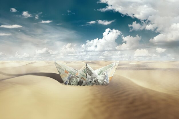 Papierowa łódź z dolarów na pustyni Łódź na pustyni i błękitne niebo Symbol kryzysu stagnacja strat stagnacja trudności brak wody pitnej susza