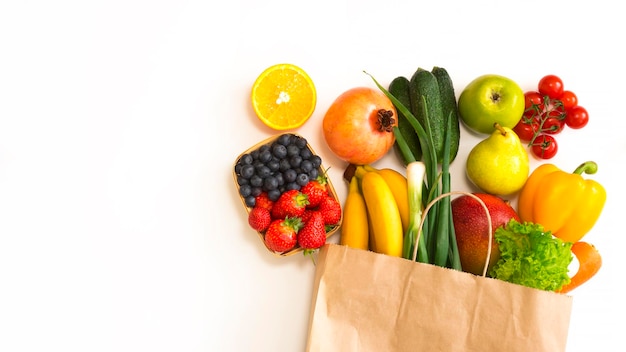 Papierowa torba z owocami i warzywami leży na białym tle