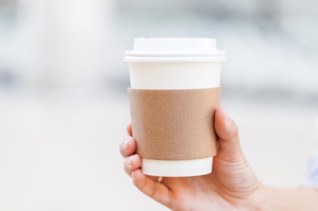 Papierowy kubek kawy na wynos w dłoni Miejsce na Twój tekst lub logo