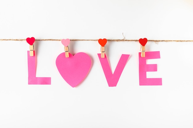 Zdjęcie papierowy miłości słowo na clothesline odizolowywającym na bielu. różowy papier na notatki na spinaczu do bielizny z sercami