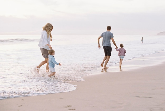 Para bawi się z synem i córką na piaszczystej plaży nad oceanem