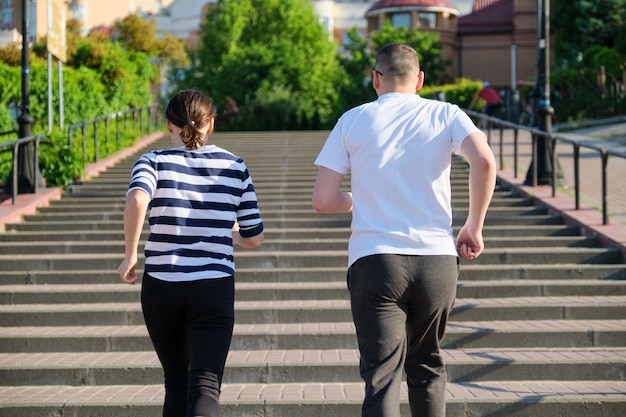 Para biegająca po schodach w widoku z tyłu miasta, dojrzały mężczyzna i kobieta razem, aktywny sport fitness zdrowy styl życia osób w średnim wieku