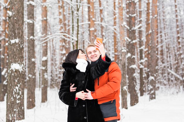 Para biorąc autoportret z inteligentnego telefonu w winter park. Piękna młoda para selfie.
