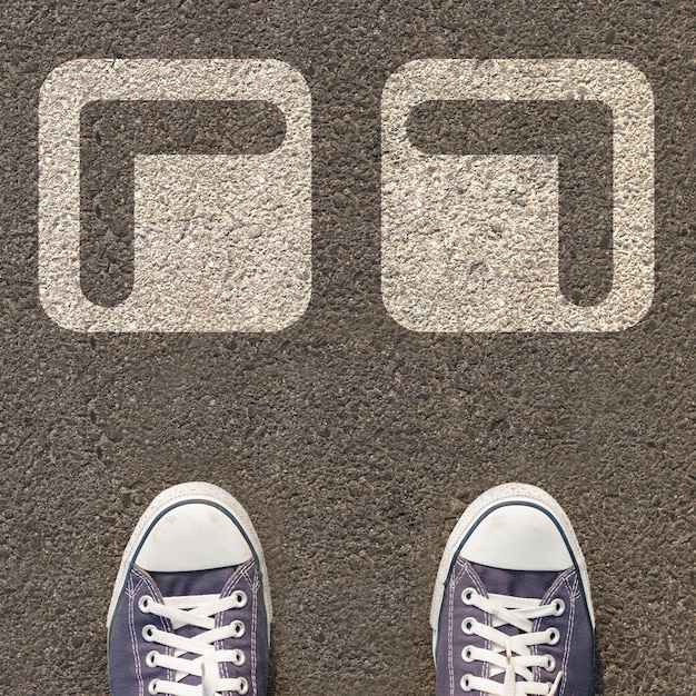 Zdjęcie para butów stojących na drodze z dwoma białymi strzałkami