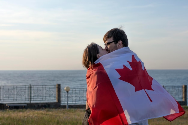 Zdjęcie para całuje się i chowa się za pasyjną flagą kanady