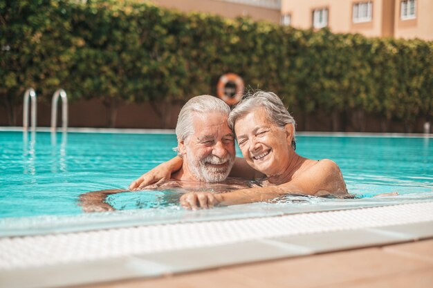 Zdjęcie para dwóch szczęśliwych seniorów bawiących się i cieszących się razem w basenie uśmiechając się i bawiąc się szczęśliwi ludzie cieszący się latem na świeżym powietrzu w wodzie