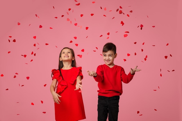 Para dziecko dziewczyna i chłopiec stoją w deszczu latających płatków róż