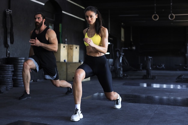 Para fitness w sportowej robienie przysiadów na siłowni.