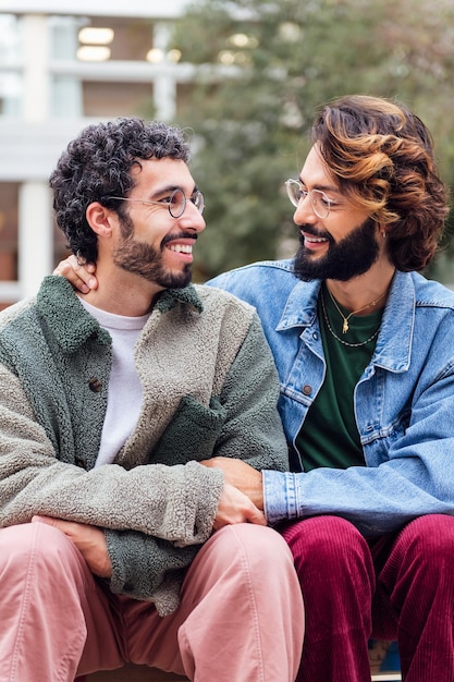 Zdjęcie para gejów siedzących w parku uśmiecha się szczęśliwa