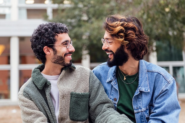 Para gejów siedzi w parku, śmiejąc się szczęśliwie