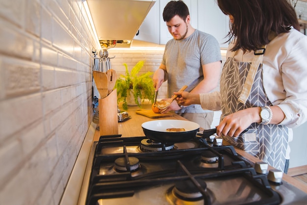 Para gotująca razem w kuchni smażąca naleśniki krojące pomarańczę