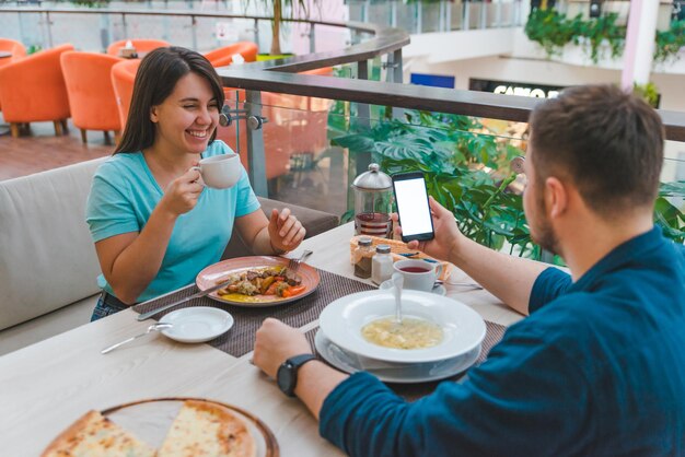 Para jedzenie w kawiarni. człowiek pokaż ekran telefonu. białe miejsce na kopię. randki