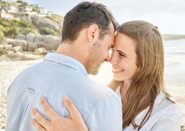 Para kocha się i przytula razem na plaży na zaręczynowy miesiąc miodowy lub rocznicę nad morzem Młody mężczyzna i kobieta uśmiechają się, czując się szczęśliwi i romantyczni nad wodą oceanu i piaskiem ze szczęścia