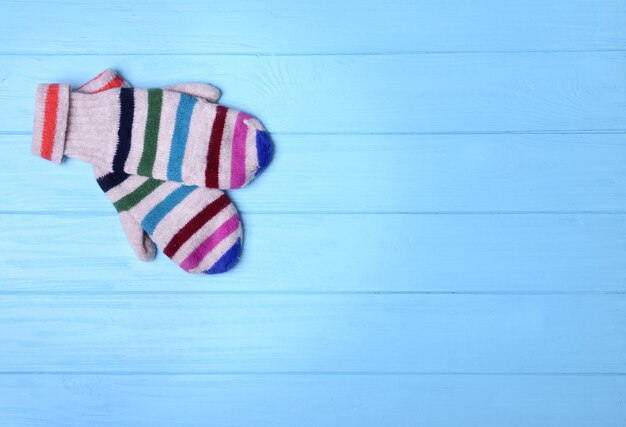 Para kolorowych rękawiczek z dzianiny na niebieskim drewnianym tle