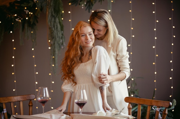 Para lesbijek jedząca kolację w restauracji. Jedna dziewczyna przytula ukochanego szepcząc jej do ucha