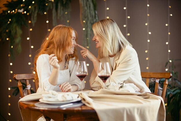 Para lesbijek jedzących obiad w restauracji. Dziewczyny piją wino i rozmawiają