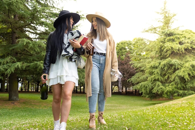 Para lesbijek spacerująca po parku z butelką szampana i kieliszkami, aby świętować zaloty