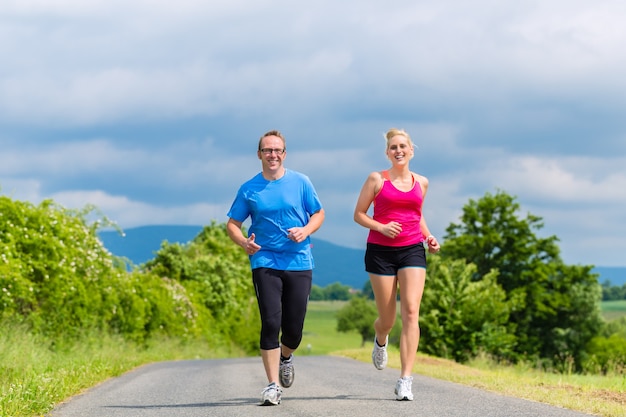 Para, mężczyzna i kobieta uprawiają jogging lub uprawiają sport na świeżym powietrzu dla fitness na wiejskiej ulicy