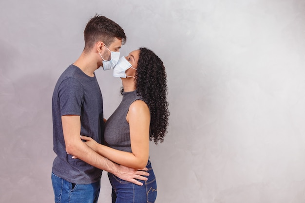 Para młodych millenialsów noszących ochronne maski na twarz i całujących się, zapobieganie rozprzestrzenianiu się wirusów i koncepcja ludzi.