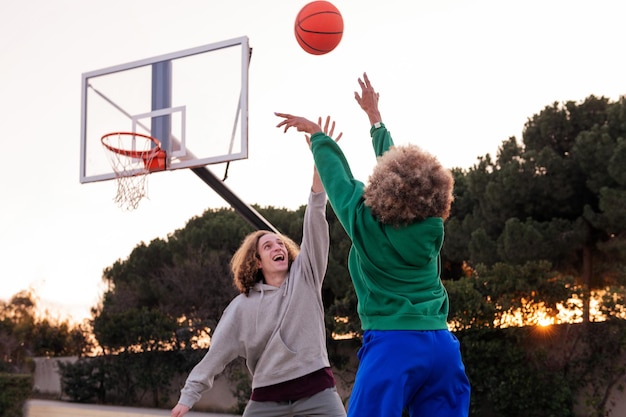 Para młodych przyjaciół grających w koszykówkę na świeżym powietrzu na miejskim boisku koncepcji miejskiego sportu na ulicy