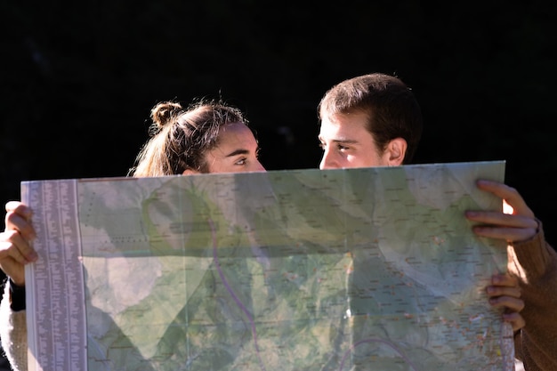 Zdjęcie para młodych turystów trzymających mapę i patrzących na siebie