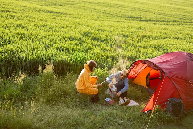 Para na kempingu z namiotem na zielonym polu