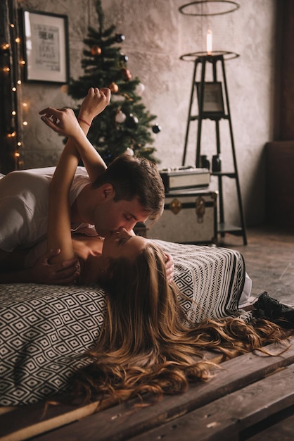 Para na łóżku w sypialni ciemne wnętrze nowy rok i bożonarodzeniowe uściski i pocałunki miłość biała sw...