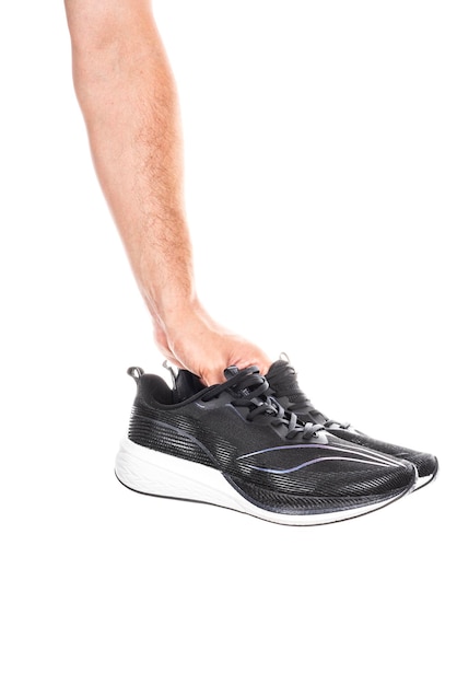 Para nowych niemarkowych czarnych sportowych butów do biegania lub trampek w męskiej dłoni na białym tle na białym tle ze ścieżką przycinającą
