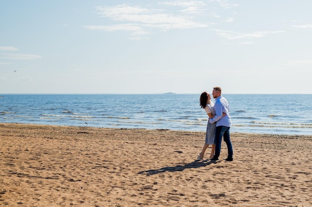 Para obejmuje się na plaży przed wodą.