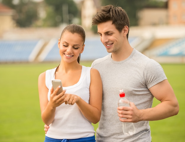 Para patrzy na smartphone podczas ćwiczeń na stadionie