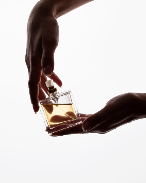 Zdjęcie para rąk delikatnie kołysze butelkę perfum