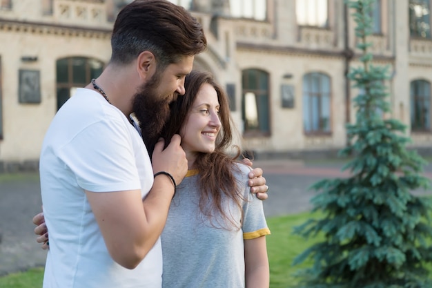 Para relaks, ciesząc się sobą. Hipster i ładna kobieta w miłości stoją w tle budynku architektury ulicy. Poczuj moją miłość. Szczęśliwi razem. Para zakochanych spaceru zabawy. Czuły uścisk.