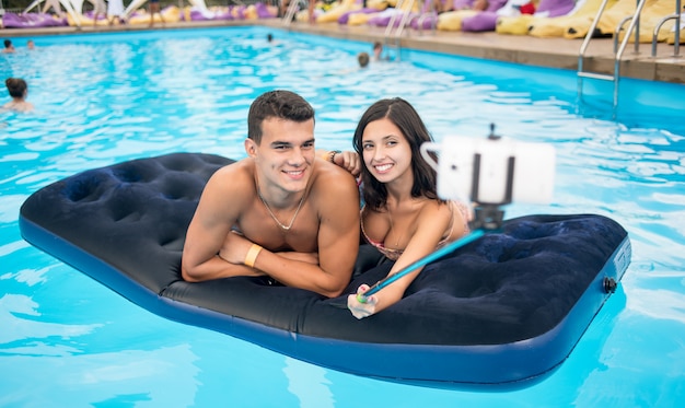 Para robi selfie fotografii na materac w basenie