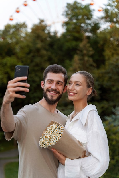 Zdjęcie para robi selfie podczas wspólnego spędzania czasu przy diabelskim młynie