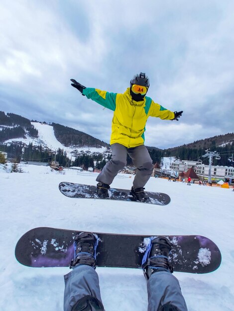 Zdjęcie para siedząca na śnieżnym wzgórzu z zimowymi zajęciami snowboardowymi