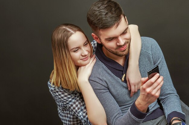 Para siedzi na czarnym tle, przystojny mężczyzna przy użyciu swojego telefonu.