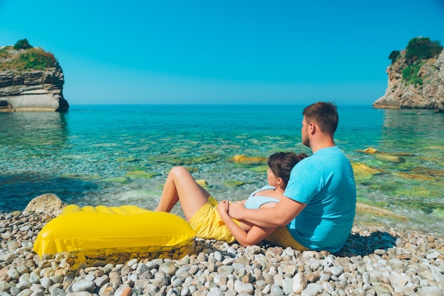 Para siedzi na kamienistej plaży patrząc na morze