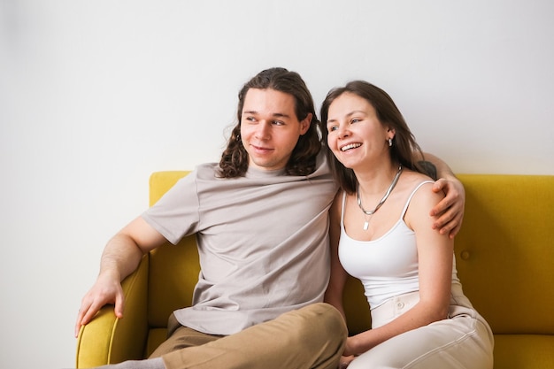 Zdjęcie para siedzi na żółtej kanapie w pokoju zakochani mężczyzna i kobieta w nowym mieszkaniu komfort w domu
