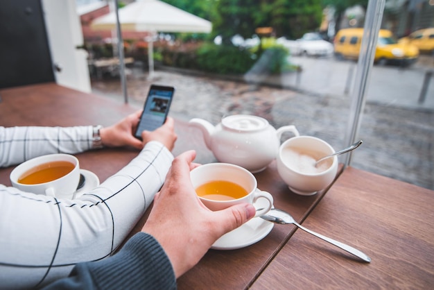 Para siedzi w kawiarni pije rozgrzaną herbatę w zimny jesienny dzień kobieta robi zdjęcie na telefonie na instagram