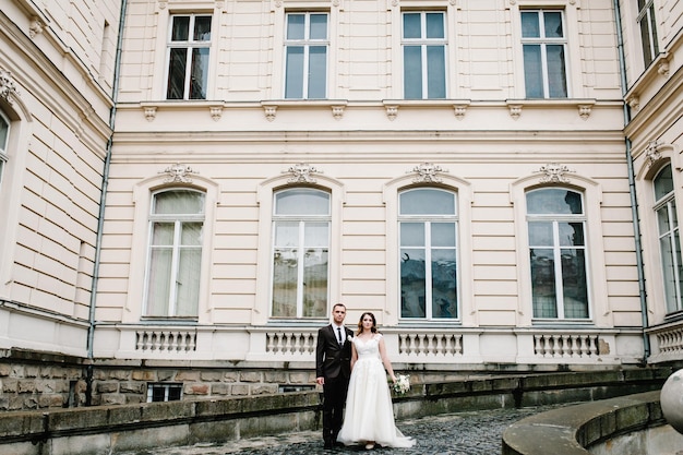 Para ślub piękny portret w pobliżu starożytnej odrestaurowanej architektury, stary budynek, stary dom na zewnątrz, zabytkowy pałac na świeżym powietrzu. Romantyczna miłość na ulicy w stylu vintage.