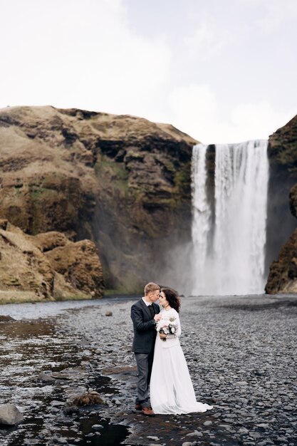 Para ślubna W Islandii W Pobliżu Wodospadu Skogafoss Panna Młoda I Pan Młody Się Przytulają