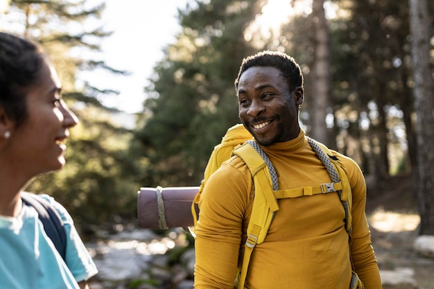 Para spacerująca razem w lesie Afroamerykanin uśmiechający się podczas rozmowy z białą kobietą w przyrodzie