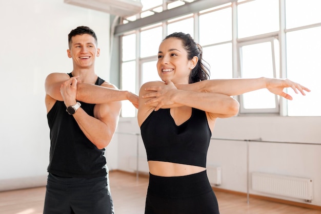 Para sportowa w stroju sportowym rozgrzewa się w siłowni rano. Dziewczyna fitness i trener.