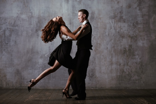 Para tancerzy w czarnej sukience tańczy tango na szarym tle vintage