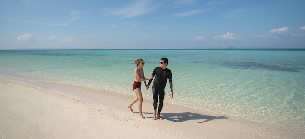 Para trzymając się za ręce i spacer po plaży, ciesząc się pięknymi wakacjami letnimi. Koncepcja stylu życia wakacje podróży