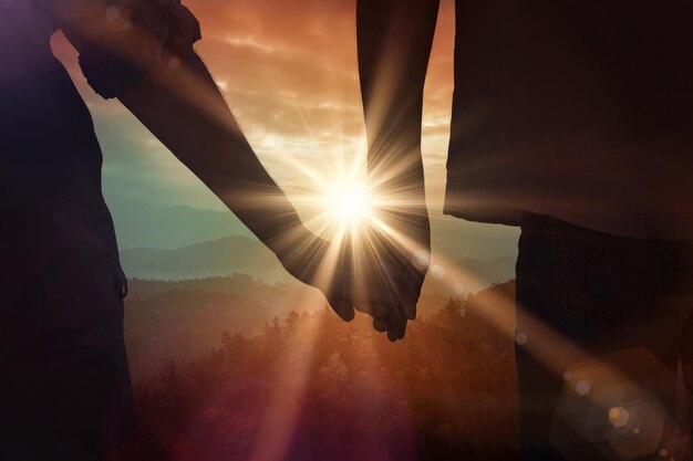 Para trzymając się za ręce w parku przed wschodem słońca nad górami