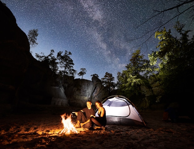 Para turystów odpoczywa obok obozu, namiot ognisko w nocy