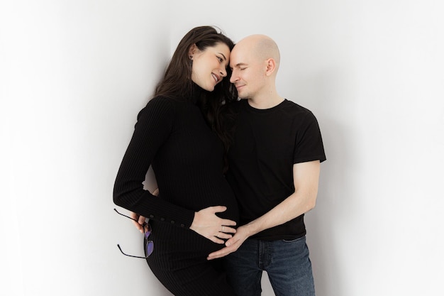 Para w ciąży w czarnych ubraniach na białym tle