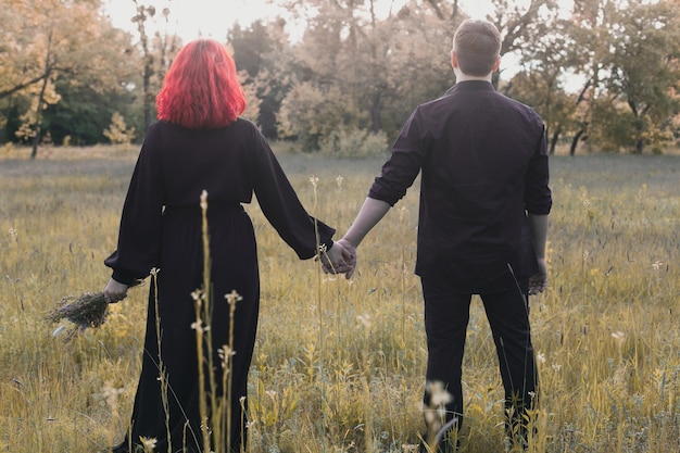 Para w ciemności trzymając się za ręce wśród łąkowej fotografii scenicznej